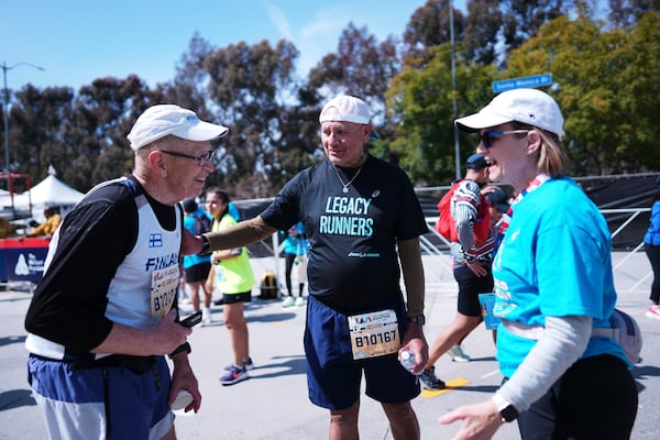 Lou Briones, center, talks to fellow runner Jussi Hamalainen, left, after they both finished the LA Marathon Sunday, March 16, 2025, in Los Angeles. (AP Photo/Eric Thayer)