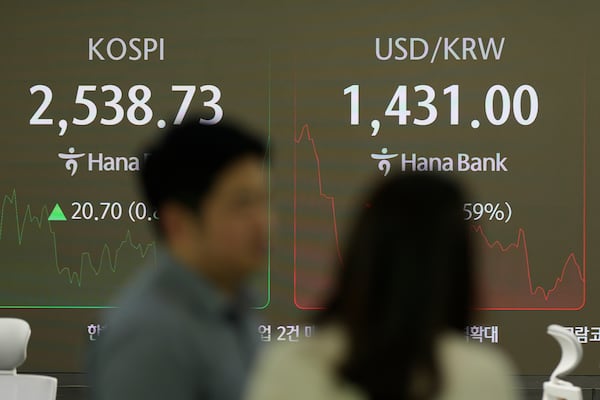 Currency traders talk near the screens showing the Korea Composite Stock Price Index (KOSPI), left, and the foreign exchange rate between U.S. dollar and South Korean won at a foreign exchange dealing room in Seoul, South Korea, Wednesday, Jan. 22, 2025. (AP Photo/Lee Jin-man)