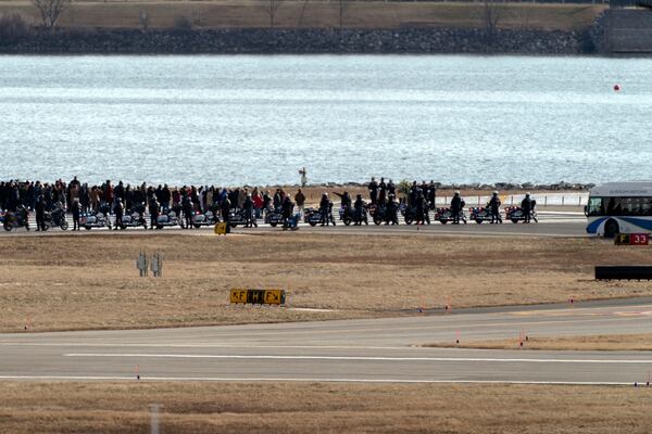 Family members of the victims of a mid-air collision between an American Airlines jet and an Army helicopter walk to the end of runway 33 near the wreckage site in the Potomac River at Ronald Reagan Washington National Airport, Sunday, Feb. 2, 2025, in Arlington, Va. (AP Photo/Jose Luis Magana)