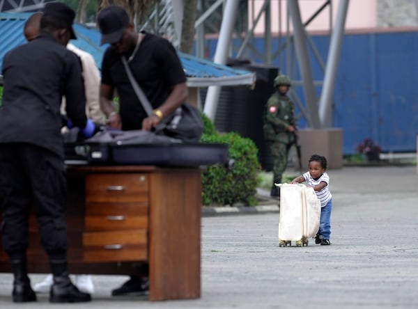 A child pushes a suitcase towards Rwanda security officials checking people crossing from Congo in Gisenyi, Rwanda, Wednesday, Jan. 29, 2025, following M23 rebels' advances into eastern Congo's capital Goma. (AP Photo/Brian Inganga)