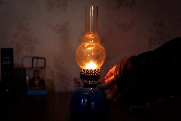 Retired teacher Vasile Donici lights a gas lamp in his home in Copanca, Moldova, Wednesday, Jan. 8, 2025. (AP Photo)