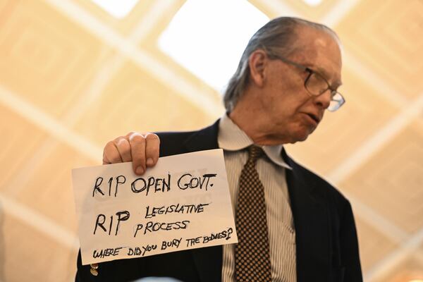 A protestor holds a sign as the Republican-dominated North Carolina House convened to complete the override of Gov. Cooper's veto, Wednesday, Dec. 11, 2024, in Raleigh, N.C. (AP Photo/Matt Kelley)