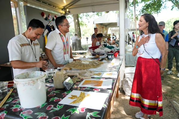 FILE - Interior Secretary Deb Haaland, right, visits a plaster art booth on opening day of the Smithsonian Folklife Festival, with its festival theme "Indigenous Voices of the Americas," Wednesday, June 26, 2024, on the National Mall in Washington. (AP Photo/Jacquelyn Martin, File)