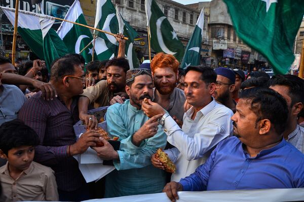 People share cake as they celebrates following India and Pakistan have reached a ceasefire deal, during a demonstration, in Hyderabad, Pakistan, Saturday, May 10, 2025. (AP Photo/Pervez Masih)