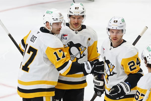 Pittsburgh Penguins right wing Bryan Rust (17) celebrates with center Sidney Crosby (87) and defenseman Matt Grzelcyk (24) after scoring during the third period of an NHL hockey game against the Buffalo Sabres, Friday, Jan. 17, 2025, in Buffalo, N.Y. (AP Photo/Jeffrey T. Barnes)