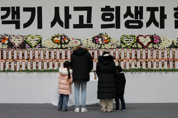 Mourners pray for the victims on a plane fire at a memorial altar at Muan sport park in Muan, South Korea, Monday, Dec. 30, 2024. The sign reads "The victims on a plane." (AP Photo/Ahn Young-joon)