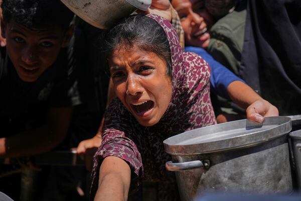 Palestinians struggle to receive cooked food distributed at a community kitchen in the Muwasi area of Khan Younis, in the Gaza Strip, Friday, May 23, 2025. (AP Photo/Abdel Kareem Hana)
