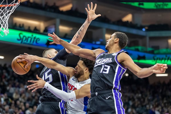 Detroit Pistons guard Cade Cunningham, center, passes the ball around Sacramento Kings center Alex Len, left, during the first half of an NBA basketball game Thursday, Dec. 26, 2024, in Sacramento, Calif. (AP Photo/Sara Nevis)