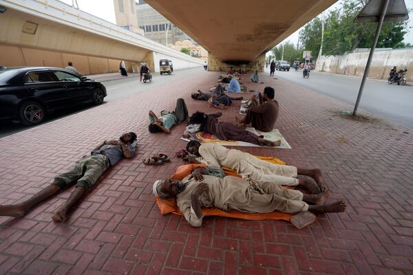 FILE - Laborers sleep under a bridge during a hot summer day in Karachi, Pakistan, Thursday, July 25, 2024. (AP Photo/Fareed Khan,File)