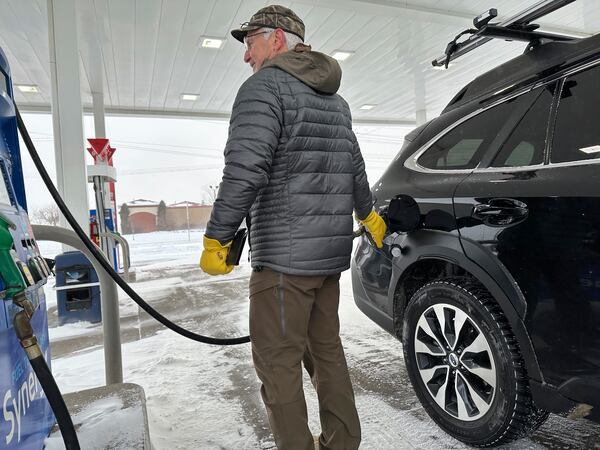 Phil Helfrich fuels up his vehicle on Thursday, Dec. 19, 2024, in Bismarck, N.D., as blustery winter weather bore down. (AP Photo/Jack Dura)