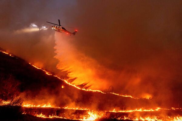 FILE -Water is dropped by helicopter on the Kenneth Fire in the West Hills section of Los Angeles, Jan. 9, 2025. (AP Photo/Ethan Swope,File)