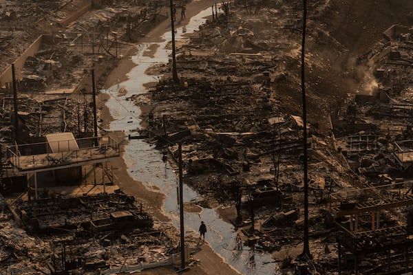 A person walks amid the destruction left behind by the Palisades Fire in the Pacific Palisades neighborhood of Los Angeles, Thursday, Jan. 9, 2025. (AP Photo/Jae C. Hong)