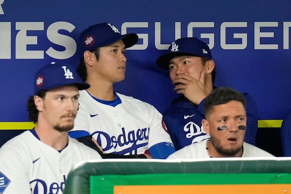 Los Angeles Dodgers' Shohei Ohtani, rear left, and Yoshinobu Yamamoto, rear right, talk as they watch a spring training baseball game against the Yomiuri Giants in Tokyo, Japan, Saturday, March 15, 2025. (AP Photo/Hiro Komae)