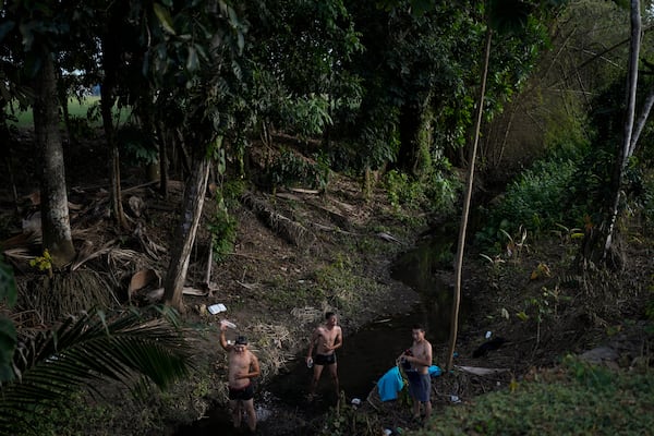 Venezuelan migrants bathe themselves in a river in Panama City, Sunday, March 2, 2025. The migrants are returning from southern Mexico after giving up on reaching the U.S., a reverse flow triggered by the Trump administration's immigration crackdown. (AP Photo/Matias Delacroix)