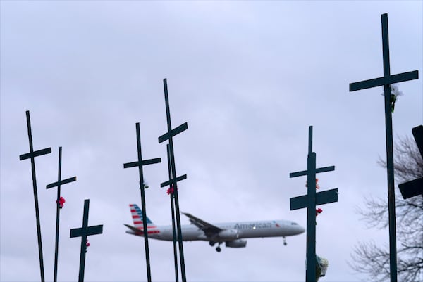 An American Airlines plane prepares to land at Ronald Reagan Washington National Airport as crosses are seen in a makeshift memorial for the victims of the plane crash in the Potomac River Friday, Jan. 31, 2025, in Arlington, Va. (AP Photo/Jose Luis Magana)