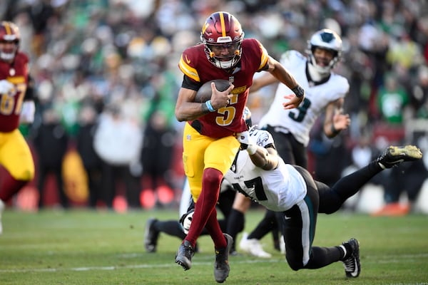 Washington Commanders quarterback Jayden Daniels (5) breaks away from Philadelphia Eagles linebacker Nakobe Dean (17) and runs with the ball during the second half of an NFL football game, Sunday, Dec. 22, 2024, in Landover, Md. (AP Photo/Nick Wass)