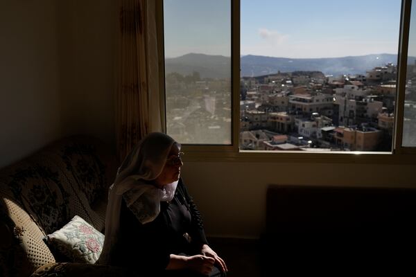 Samar Safadi sits next to a window after speaking by phone with her sister, Sawsan, who lives inside the buffer zone near the "Alpha Line" that separates the Israeli-controlled Golan Heights from Syria, in the town of Majdal Shams, Wednesday, Dec. 18, 2024. (AP Photo/Matias Delacroix)