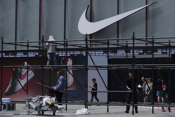Shoppers walk by as workers install a platform near a Nike store outside a shopping mall in Beijing, Sunday, May 11, 2025. (AP Photo/Andy Wong)
