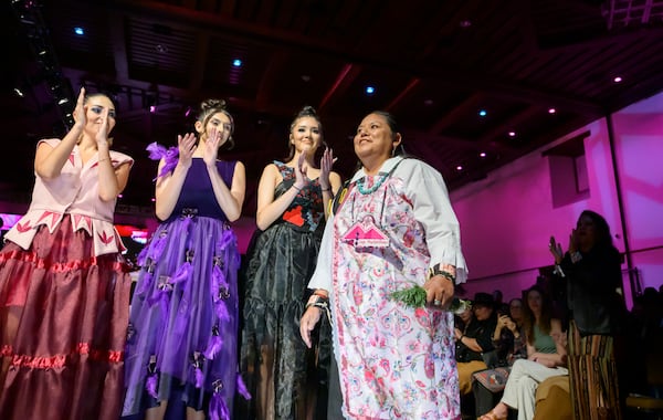Designer Sage Mountainflower, right, receives a round of applause after her runway show at the 2025 Native Fashion Show, Friday, May 9, 2025, in Santa Fe, N.M. (AP Photo/Roberto E. Rosales)