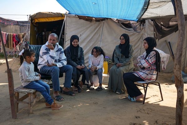 Members of the Abu Jarad family, who were displaced by the Israeli bombardment of the Gaza Strip, gather in front of their tent at a camp for displaced Palestinians in the Muwasi area, southern Gaza Strip, Saturday, Jan. 18, 2025. (AP Photo/Abdel Kareem Hana)