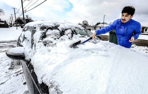 University of Louisville student Alex Hernandez scrapes the ice and snow from the front windshield of his car, Wednesday, Jan. 8, 2025, in Owensboro, Ky, while getting the vehicle ready to drive back to the college after being home for winter break. (Greg Eans/The Messenger-Inquirer via AP)