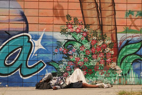 A person sleeps on a sidewalk, Monday, May 12, 2025, in Los Angeles. (AP Photo/Damian Dovarganes)