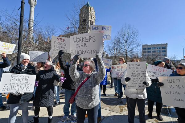 Protesters carry signs under the Columbus Statue at the Scranton Court House Square at a "Save Steamtown" rally to protest the Trump administration layoffs at the Steamtown National Historic Site in Scranton, Pa., Saturday, Feb. 22, 2025. (Aimee Dilger/WVIA via AP)