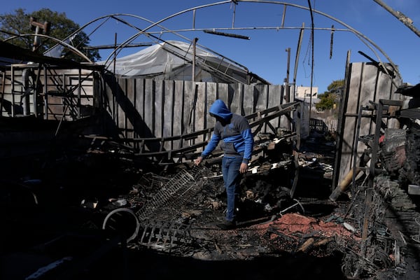 A Palestinian youth sifts through the aftermath of an attack by Israeli settlers in the West Bank village of Jinsafut, Tuesday, Jan. 21, 2025. (AP Photo/Majdi Mohammed)