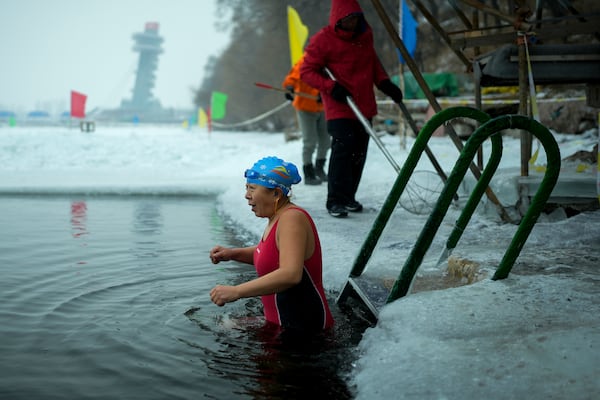 A woman reacts as she gets into a pool carved from ice on the frozen Songhua river in Harbin in northeastern China's Heilongjiang province, Tuesday, Jan. 7, 2025. (AP Photo/Andy Wong)