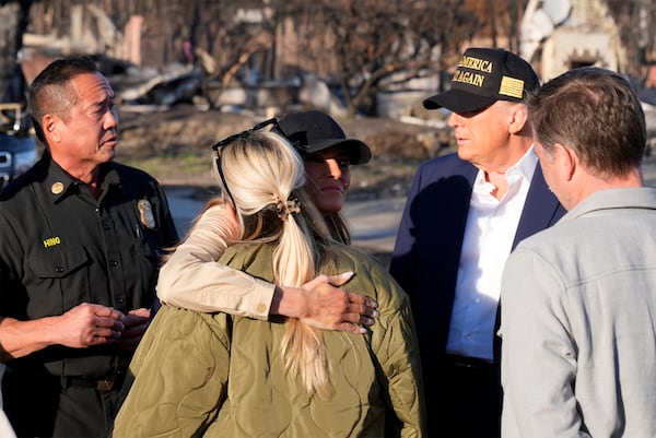 President Donald Trump watches as first lady Melania Trump hugs a resident, as they tour the Pacific Palisades neighborhood affected by recent wildfires in Los Angeles, Friday, Jan. 24, 2025. (AP Photo/Mark Schiefelbein)