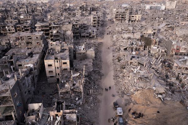 An aerial photograph taken by a drone shows Palestinians walking through the destruction caused by the Israeli air and ground offensive, in Rafah, Gaza Strip, Tuesday, Jan. 21, 2025. (AP Photo/Mohammad Abu Samra)