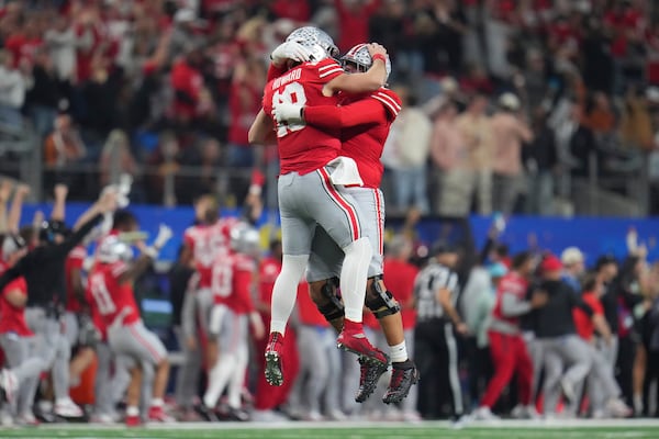 Ohio State quarterback Will Howard, middle left, is congratulated by offensive lineman Josh Fryar after throwing a touchdown pass during the first half of the Cotton Bowl College Football Playoff semifinal game against Texas, Friday, Jan. 10, 2025, in Arlington, Texas. (AP Photo/Julio Cortez)