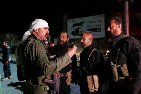 A Druze gunman, left, speaks with Syrian security forces who reached a deal with Druze gunmen to deploy around the southern Damascus suburb of Jaramana that has witnessed fighting earlier this week in Damascus, Syria, early Friday, May 2, 2025. (AP Photo/Omar Sanadiki)