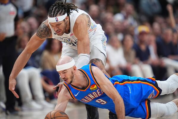 Oklahoma City Thunder guard Alex Caruso, front, dives for a loose ball in front of Denver Nuggets forward Aaron Gordon in the second half of Game 6 in the Western Conference semifinals of the NBA basketball playoffs Thursday, May 15, 2025, in Denver. (AP Photo/David Zalubowski)