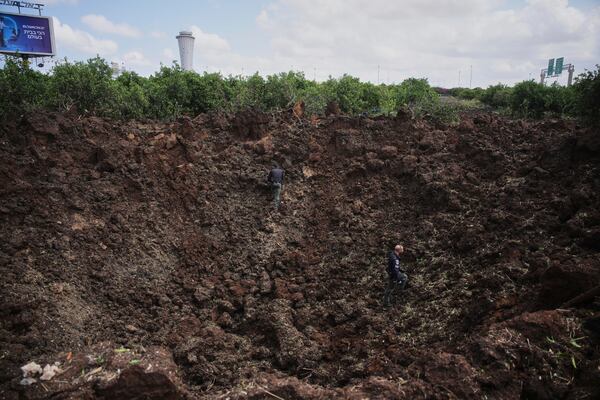 Israeli security forces inspect a crater at the site where the Israeli military said a projectile fired by Yemen's Houthi rebels landed in the area of Ben Gurion International Airport near Tel Aviv, Israel, on Sunday, May 4, 2025. (AP Photo/Ohad Zwigenberg)