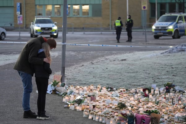 People comfort each other at a makeshift memorial, near the scene of a shooting, on the outskirts of Orebro, Sweden, Friday, Feb. 7, 2025. (AP Photo/Sergei Grits)