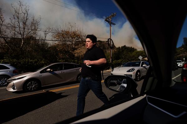 A person flees from an advancing wildfire in the Pacific Palisades neighborhood of Los Angeles Tuesday, Jan. 7, 2025. (AP Photo/Ethan Swope)