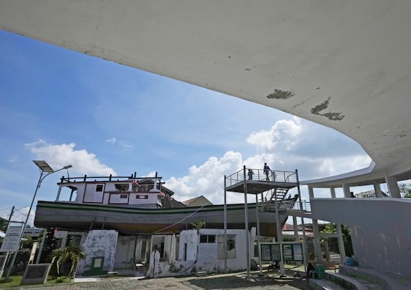 Visitors stand on a platform near a house on which a fishing boat landed after it was swept ashore by the Indian Ocean tsunami in 2004, now preserved as a monument, in Banda Aceh, Indonesia, Friday, Dec. 13, 2024. (AP Photo/Achmad Ibrahim)