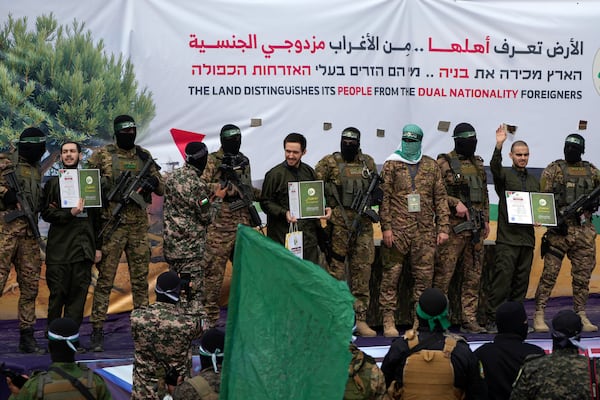 Israeli hostages Eliya Cohen, left, Omer Shem Tov and Omer Wenkert are escorted by Hamas fighters before being handed over to the Red Cross in Nuseirat, central Gaza Strip, Saturday, Feb. 22, 2025. (AP Photo/Abdel Kareem Hana)