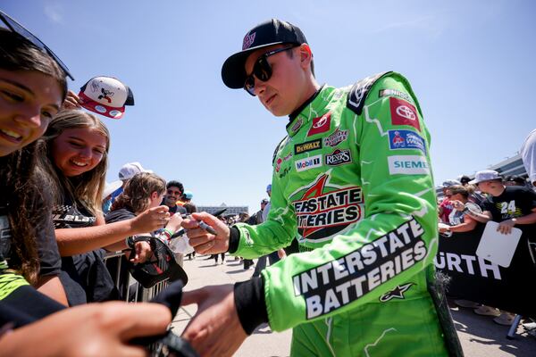 Christopher Bell, right, autographs a fan's shirt before a NASCAR Cup Series auto race at Texas Motor Speedway in Fort Worth, Texas, Sunday, May 4, 2025. (AP Photo/Gareth Patterson)
