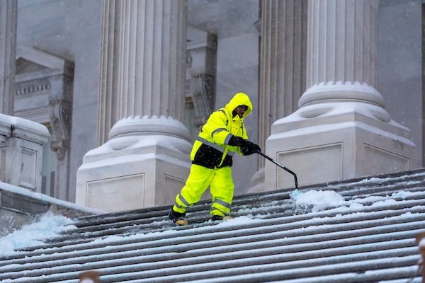 A workman clears steps at the Capitol as snow falls ahead of a joint session of Congress to certify the votes from the Electoral College in the presidential election, in Washington, Monday, Jan. 6, 2025. (AP Photo/J. Scott Applewhite)