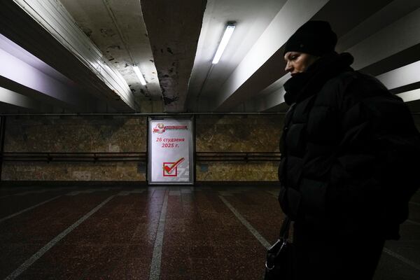 A woman walks past an election poster ahead of presidential elections in Minsk, Belarus, Friday, Jan. 24, 2025. (AP Photo/Pavel Bednyakov)