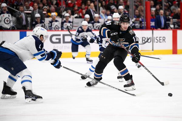 Washington Capitals center Dylan Strome (17) passes the puck against Winnipeg Jets defenseman Neal Pionk, left, during the first period of an NHL hockey game, Saturday, Feb. 1, 2025, in Washington. (AP Photo/Nick Wass)