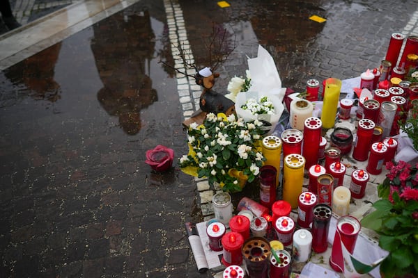 People are reflected in a puddle as they pray for Pope Francis in front of the Agostino Gemelli Polyclinic, in Rome, Wednesday, March 12, 2025, where the Pontiff is hospitalized since Friday, Feb. 14. (AP Photo/Andrew Medichini)