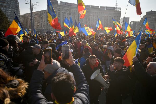 Supporters of Calin Georgescu, the winner of Romania's first round of presidential elections, wave flags and chant slogans in front of the government headquarters, in Bucharest, Romania, Monday, Feb. 10, 2025. (AP Photo/Alexandru Dobre)