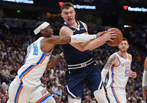 Oklahoma City Thunder guard Shai Gilgeous-Alexander, left, blocks Denver Nuggets guard Christian Braun, front right, on the way to the basket in the first half of Game 4 in the Western Conference semifinals of the NBA basketball playoffs Sunday, May 11, 2025, in Denver. (AP Photo/David Zalubowski)