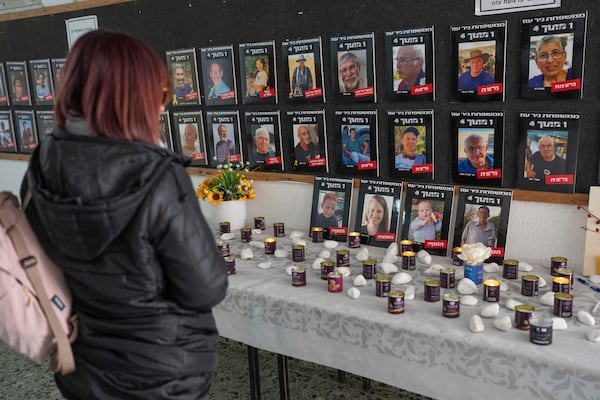 A woman looks at photos of slain hostages (bottom row, L-R) Ariel Bibas, his mother Shiri, his brother, Kfir and Oded Lifshitz, right, that are displayed in the dining hall at Kibbutz Nir Oz, in southern Israel, on Tuesday, Feb. 25, 2025. (AP Photo/Ohad Zwigenberg)