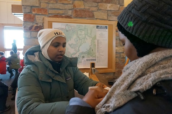 Nasrieen Habib, left, helps Isho Mohamed with her snow tubing pass during an outing organized by the group Habib founded to promote outdoors activities among Muslim women, at Elm Creek Park Reserve in Maple Grove, Minn., on Jan. 4, 2025. (AP Photo/Giovanna Dell'Orto)