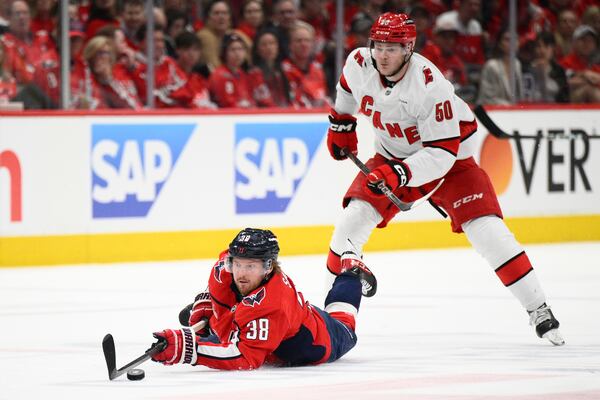 Washington Capitals defenseman Rasmus Sandin (38) dives for the puck past Carolina Hurricanes left wing Eric Robinson (50) in the second period of Game 2 of a second-round NHL hockey playoff series Thursday, May 8, 2025, in Washington. (AP Photo/Nick Wass)