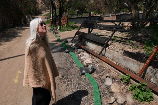 Kathryn Frazier looks at property, which was destroyed by the Eaton Fire in Altadena, Calif., on Tuesday, April 22, 2025. (AP Photo/Damian Dovarganes)